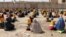 Afghans sit on the ground after they receiving ration aid in Kandahar last month. 