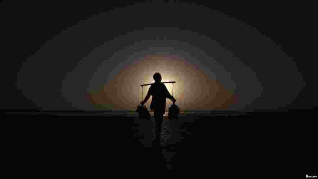 Twenty-year-old Rahmet Gul is silhouetted against the setting sun as he waits to sell green tea to customers along Karachi's Clifton beach on October 2. (REUTERS/Athar Hussain)