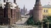 An entrance to Moscow&#39;s Red Square, with St. Basil&#39;s Cathedral in the distance, and the State Historical Museum to the left. Thousands of people can be seen standing in a long, snaking line to enter Lenin&#39;s mausoleum.