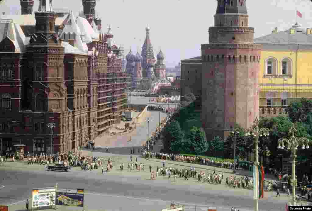 An entrance to Moscow&#39;s Red Square, with St. Basil&#39;s Cathedral in the distance, and the State Historical Museum to the left. Thousands of people can be seen standing in a long, snaking line to enter Lenin&#39;s mausoleum.