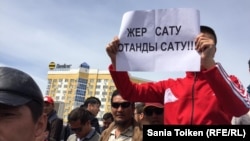 Митинг в Атырау против предложенной властями земельной реформы. Участник акции протеста держит плакат с надписью: «Продать землю – продать родину». 24 апреля 2016 года. 