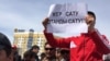 Участник митинга держит плакат с надписью: «Продать землю — продать родину»
