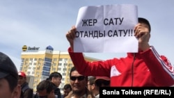 Участник митинга держит плакат с надписью: «Продать землю — продать родину»