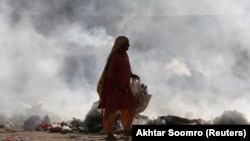 An elderly woman searches for recyclables from a roadside dump in Karachi.