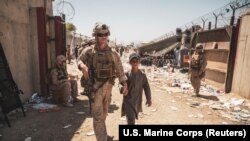 Морской пехотинец США сопровождает ребенка к семье во время эвакуации в аэропорту Кабула, 24 августа 2021 года.