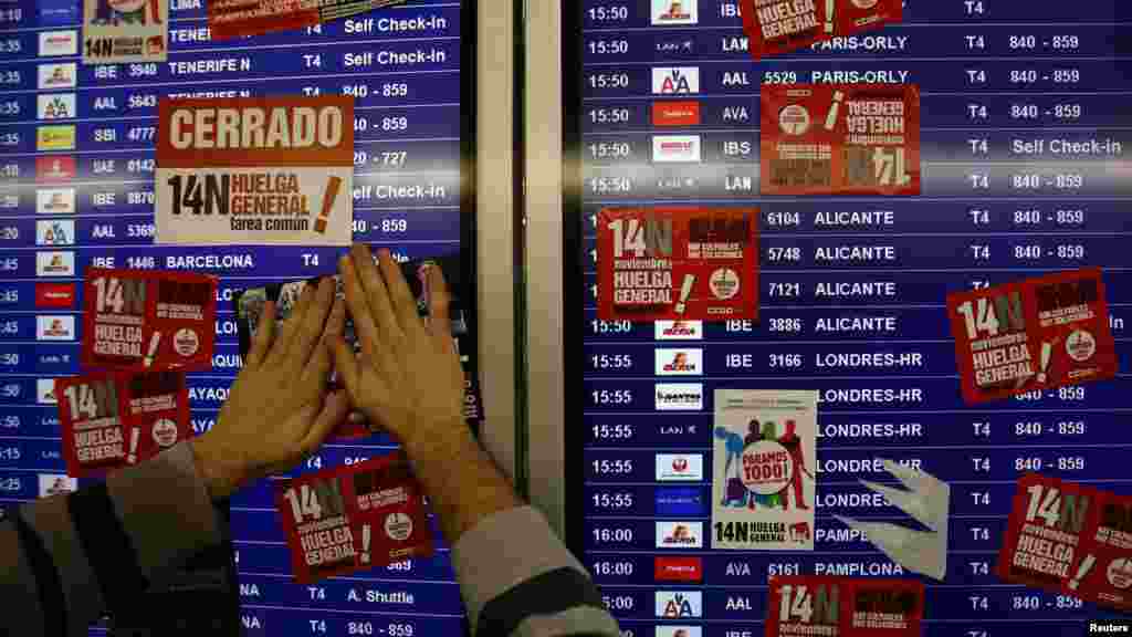 A striking union worker posts a sticker on a screen at Madrid&#39;s Barajas airport.