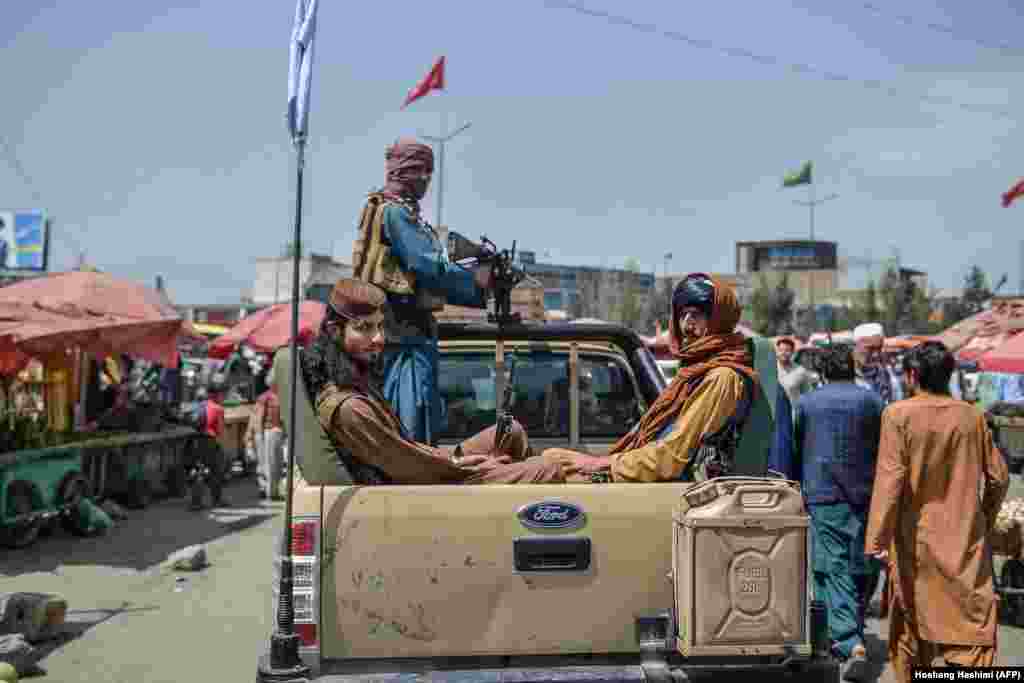 Taliban fighters on a pickup truck move around a busy market area in the Kote Sangi area of Kabul on August 17.