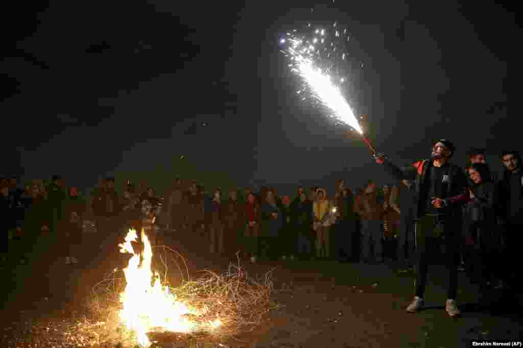 A man holds up a firework during Chaharshanbe Souri, or Wednesday Feast, an ancient Festival of Fire, on the eve of the last Wednesday of the solar Persian year, in Tehran, Iran, Tuesday, March 19, 2019.