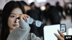 زنی در حال آزمایش عینک «روکید» با نمایشگر و دوربین، که از هوش مصنوعی بهره می‌گیرد