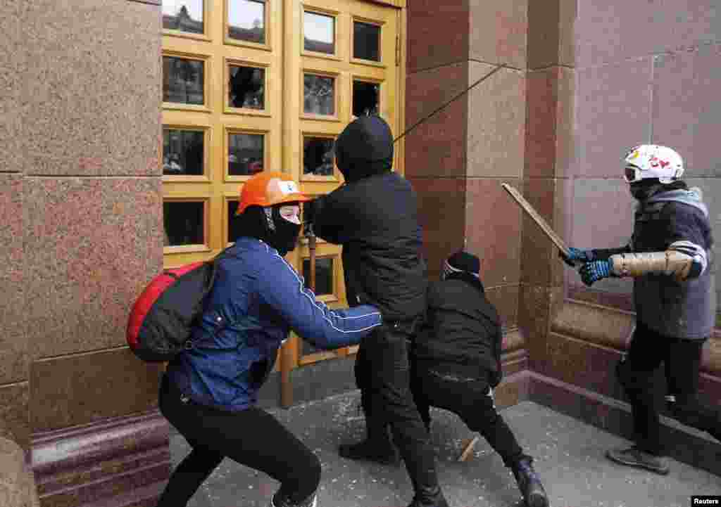 Unidentified men attempt to break into a Kyiv city council building during the rally.