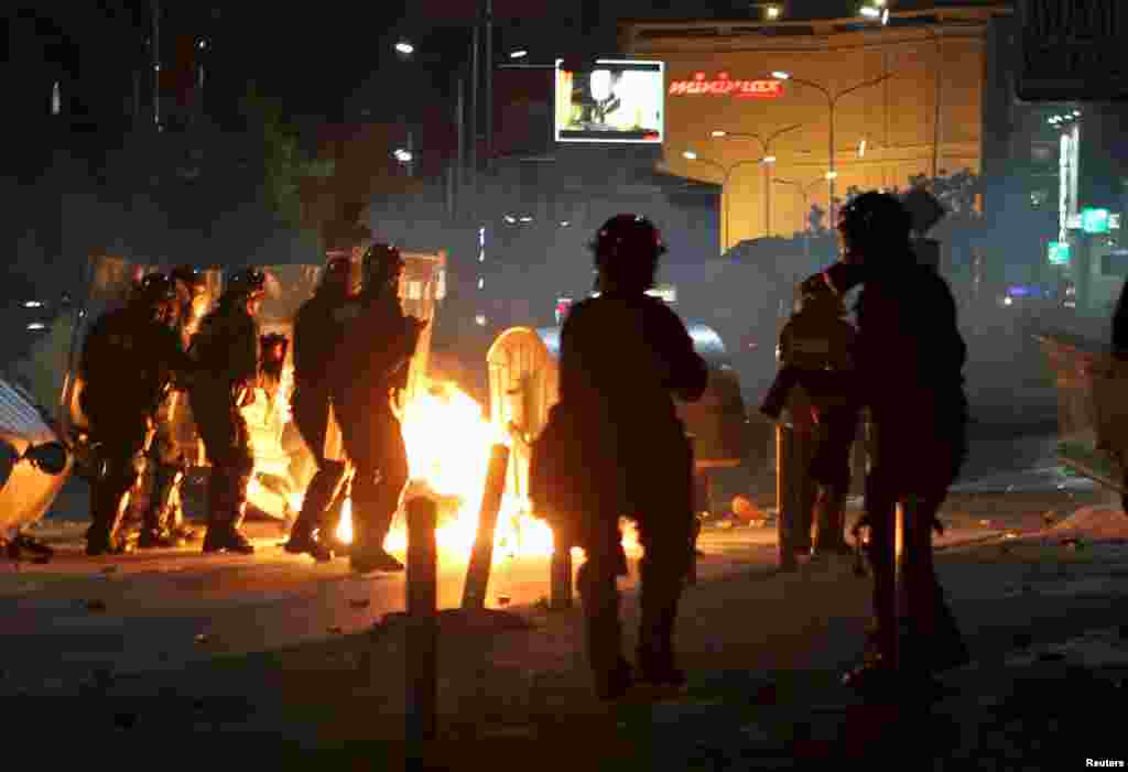 Police are seen next to a fire caused by a Molotov cocktail thrown by protesters in Kosovo&#39;s capital. Protesters besieged the central police station in Pristina, hours after the detention of a prominent opposition politician, lobbing concrete and stones at police, who returned fire with tear gas. (Reuters/Hazir Reka )