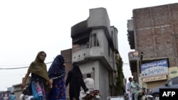 Pedestrians walks past the smoke-charred house of an Ahmadi following an attack by an angry mob in the eastern city of Gujranwala, in the Punjab province on July 28, 2014. An angry 