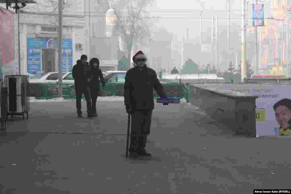 Бездомный в шапке Санта-Клауса просит подаяние у супермаркета, Бишкек.
