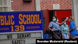 Офицеры школьной безопасности проверяют температуру учителя в Бруклинском районе Нью-Йорка.