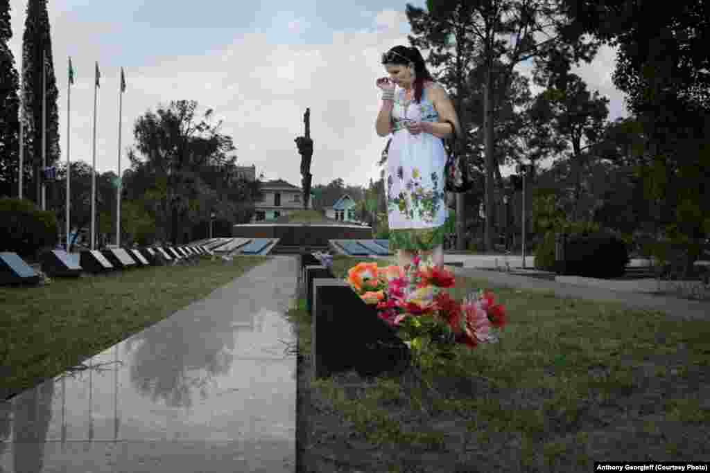 A woman lays flowers at the grave of a relative killed in the 1992-1993 war. A square in central Sukhumi has been turned into a large cemetery.