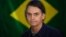 BRAZIL -- Brazil's right-wing presidential candidate for the Social Liberal Party (PSL) Jair Bolsonaro gestures in front of the Brazilian flag as he prepares to cast his vote during the general elections, in Rio de Janeiro, October 7, 2018