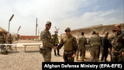 A U.S. soldier and an Afghan National Army (ANA) soldier shake hands during a handover ceremony to the ANA of a camp in Helmand Province on May 2.