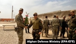 A U.S. soldier and an Afghan soldier shake hands during a handover ceremony in Helmand on May 2.
