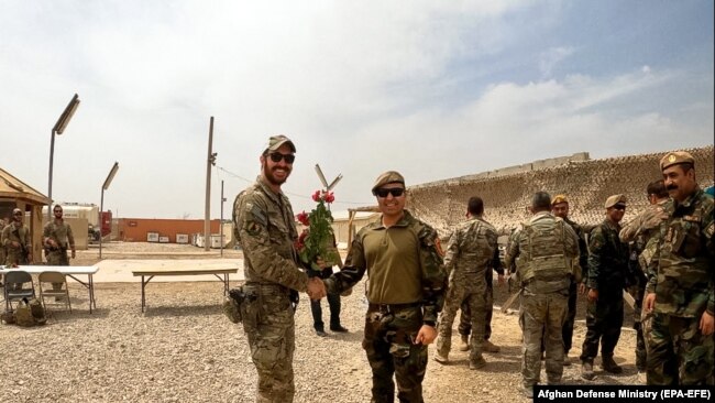 Një ushtar amerikan dhe një ushtar afgan shtrëngojnë duart gjatë një ceremonie të dorëzimit të detyrave në provincën Helmand, më 2 maj.
