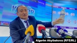Глава Минздрава Алымкадыр Бейшеналиев на пресс-конференции демонстрирует бутылку с отваром иссык-кульского корня. Бишкек. 16 апреля 2021 года.