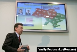 Ukraine's Central Election Commission head Serhiy Kivalov passes a screen with preliminary results of the presidential run-off vote early on November 22, 2004.