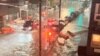 A vehicle moves along a flooded road as safety barriers float in floodwaters in Williamsburg, in the Brooklyn borough of New York City, New York, U.S. September 1, 2021
