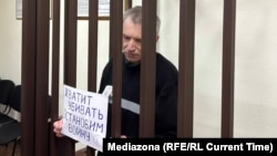 Former Moscow city duma Deputy Aleksei Gorinov appears in court on November 27 with a handmade poster calling for an end to the war in Ukraine.