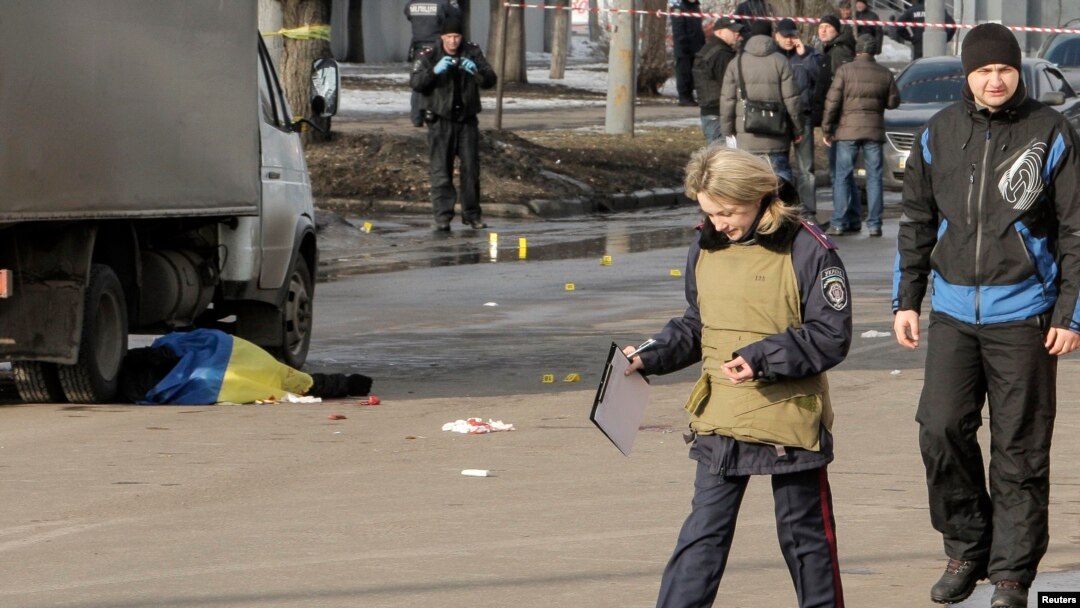 A policewoman walks near the body of a victim covered by a Ukrainian national flag at the site of a bomb attack in Kharkiv on February 22 which killed three people. 