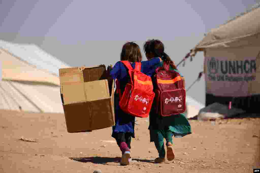 Children walk past UNHCR temporary shelter tents as they head to school on the first day of classes at a refugee camp housing Iraqi displaced families in the Kurdish town of Derik (aka Al-Malikiyah in Arabic), in northeastern Syria. (AFP/Delil Souleiman)