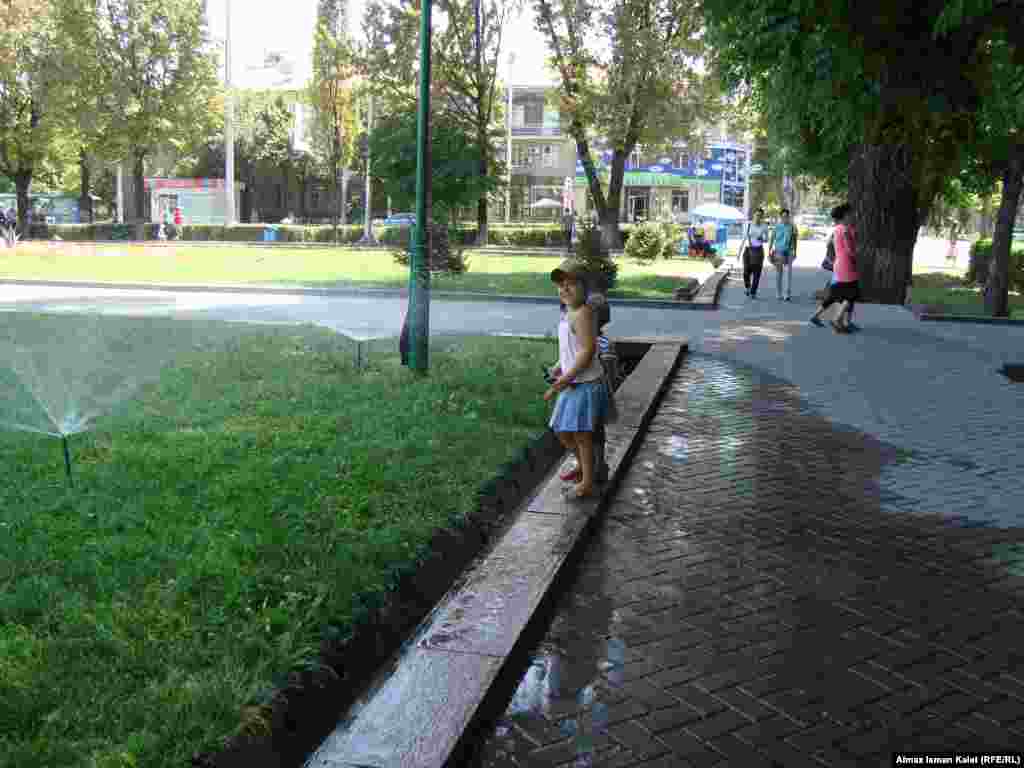 Летний Бишкек - Детвора с восторгом и визгом купается в брызгах воды от поливальных фонтанчиков. 