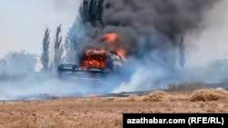 Комбайн на поле, охваченный пламенем и густым чёрным дымом
