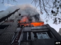 Fotografie difuzată de Serviciul de Urgență al Ucrainei pe 30 iulie 2026: un salvator stinge un incendiu într-un bloc din Lvov, după un atac rusesc.