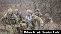 Павло Чиркін (крайній зліва) допомагає виносити пораненого з поля бою 