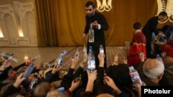 Armenia - A clergyman hands out bottles of holy water to worshippers after a Christmas mass in St. Gregory's Cathedral in Yerevan, January 6, 2019.