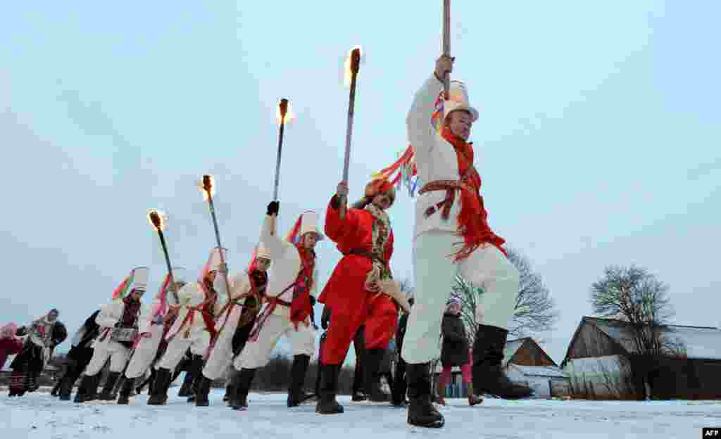 Local residents dressed in traditional Belarusian costumes hold torches and march as they perform traditional &quot;Kolyady&quot; rituals in the village of Semezhevo on January 13. (AFP/Viktor Drachev)