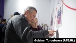 Чыңгыз Айтматовдун карындашы Роза Айтматова жазуучунун чыгармаларынын каармандарына арналган сүрөттөрдү көрүп жатат. Буга чейин тартылган сүрөт. Иллюстрация.
