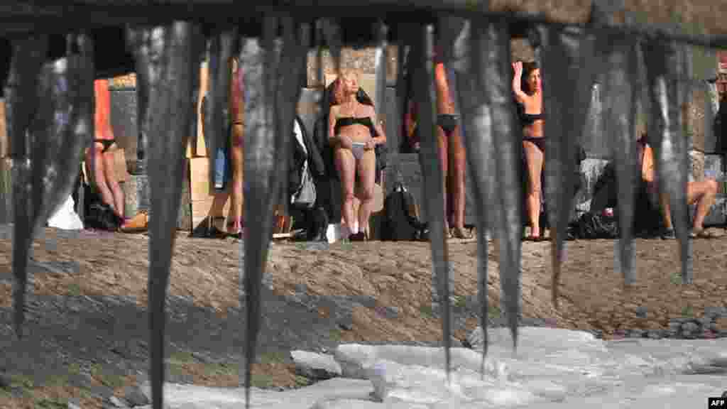 A picture taken through icicles shows people sunbathing on the wall of the Saint Peter and Paul fortress in central Saint Petersburg on April 2 as the temperature reached 2 degrees Celsius (36 degrees Fahrenheit). (AFP/Olga Maltseva) 