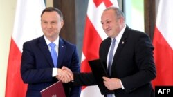 Georgian President Giorgi Margvelashvili (right) and Polish counterpart Andrzej Duda exchange documents during a joint press conference following their meeting in Tbilisi on May 30.