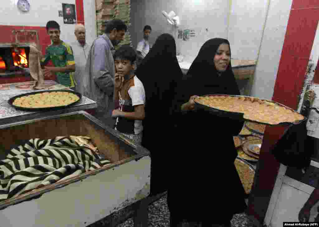 A woman carries a tray of sweets that are prepared at a bakery for the occasion of Eid al-Fitr holiday in Baghdad’s Sadr City neighborhood in Iraq.