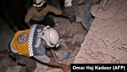 Syrian rescuers known as White Helmets recover bodies in Zardana following air strikes in June.