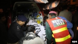 Rescue workers and police move the bodies of the victims of a suicide bomb attack in Lahore on November 2, 2014.