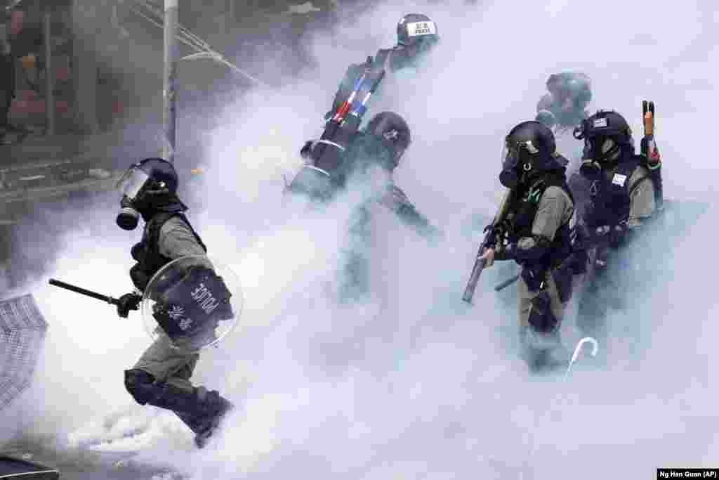 Поліція у спорядженні для розгону демонстрантів рухається через димову хмару в Гонконгському політехнічному університеті в Гонконзі, 18 листопада 2019 року