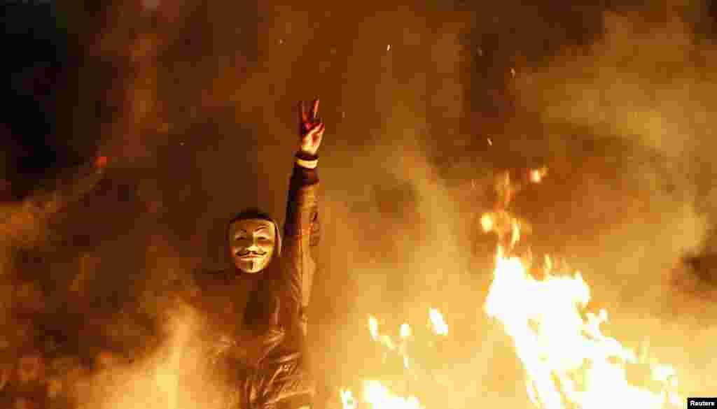 A Turkish antigovernment protester gestures behind a burning barricade during a demonstration in Ankara on March 12. (Reuters/Umit Bektas)