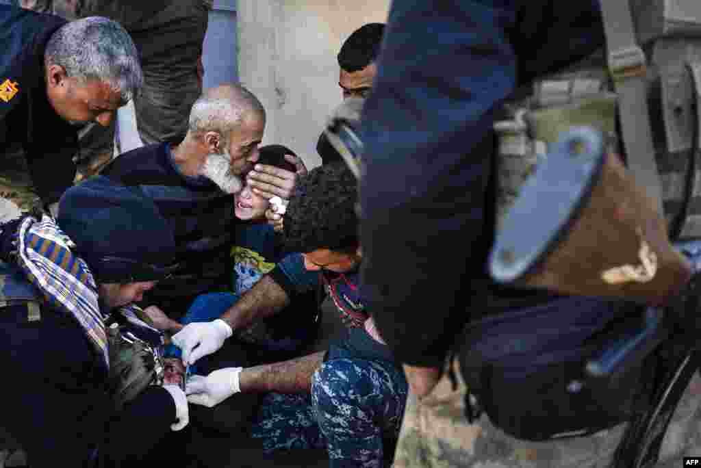 An elderly Iraqi man comforts a wounded boy as he receives treatment from military doctors in Mosul during a military operation by Iraqi security forces against Islamic State militants. (AFP/Dimitar Dilkoff)