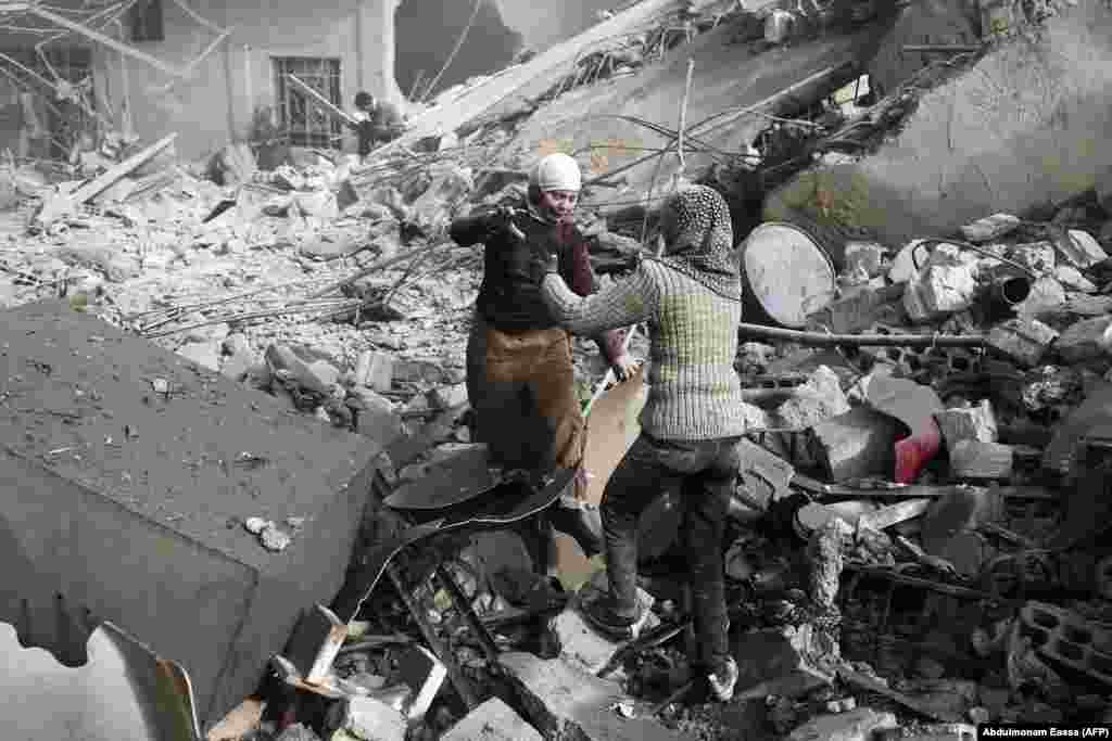 Two Syrian sisters run across rubble to embrace after finding each other alive following an air strike on Hamouria, in the besieged rebel-held Eastern Ghouta area near Damascus, on January 9. (AFP/Abdulmonam Eassa)