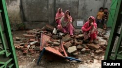 Villagers sit on the debris of their house after it was damaged during the recent exchange of fire between Pakistan and India at the Pakistani border town of Dhamala Hakimwala near Sialkot on October 8, 2014. 