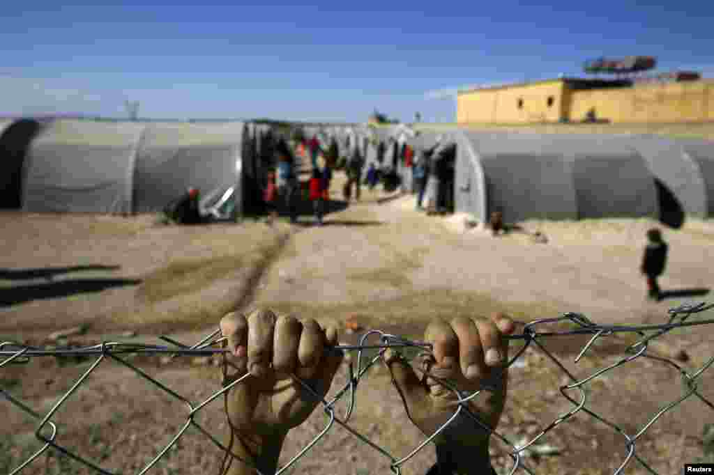 A Kurdish refugee from the Syrian town of Kobani holds onto a fence that surrounds a refugee camp in the border town of Suruc, in Turkey&#39;s Sanliurfa Province. (Reuters/Yannis Behrakis) 