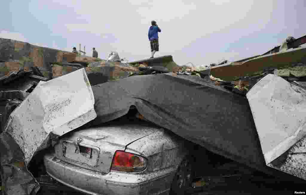 A resident stands on top of wreckage after the tornado struck the town, destroying dozens of homes, two schools, and a hospital.