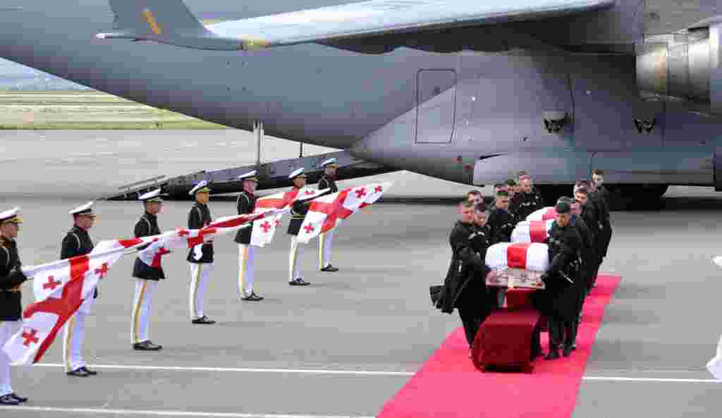 An honor guard carries the coffins of three Georgian soldiers killed in Afghanistan at the airport in Tbilisi.