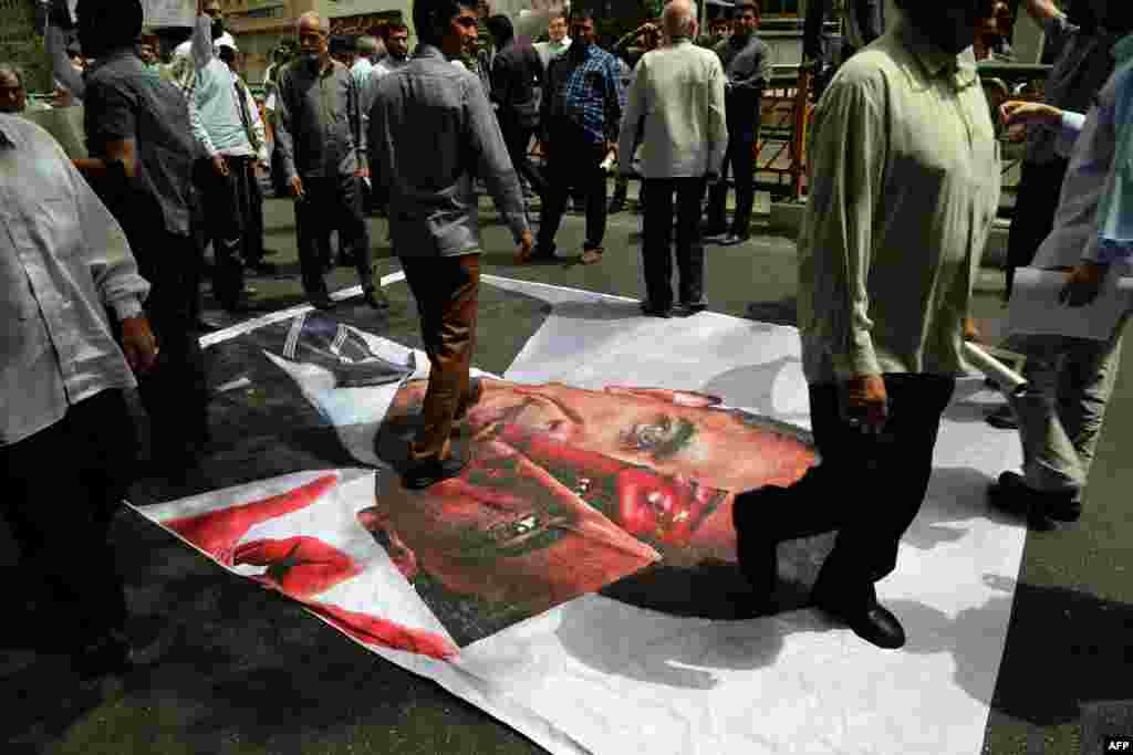 Iranians walk over a picture of U.S. President Barack Obama following the weekly Friday Prayer ceremony in Tehran. (AFP/Atta Kenare)